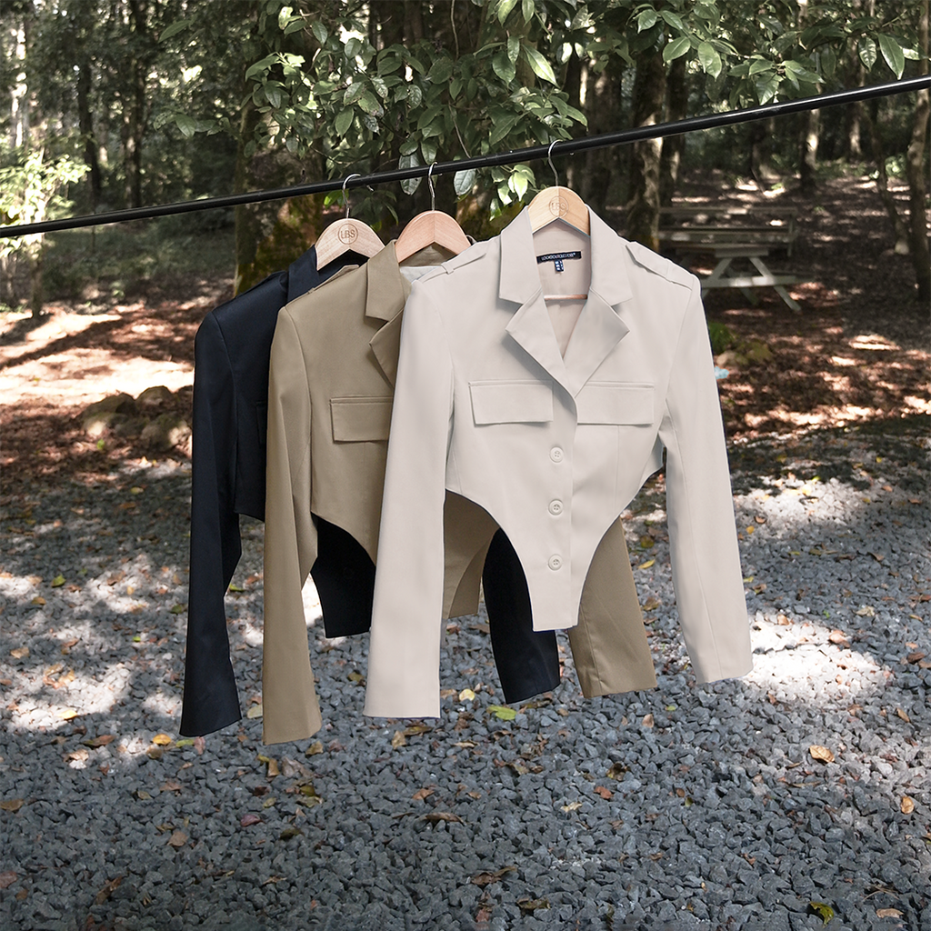 Three differently colored blazers hanging against a forest background.